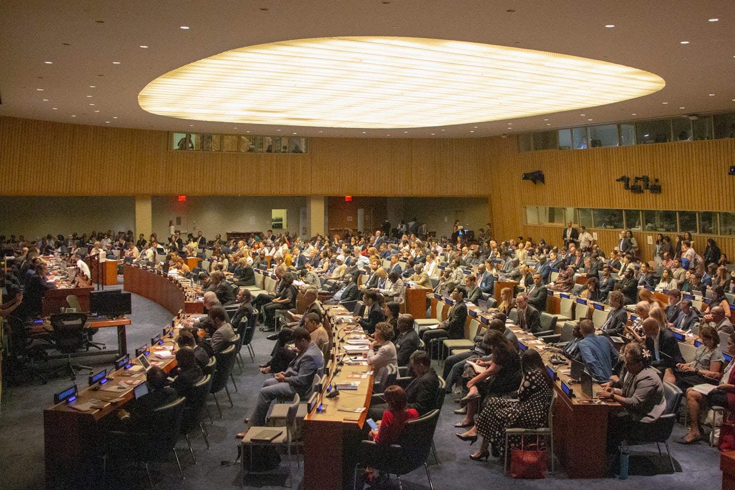 Delegates seated at desks in a large conference hall.